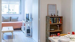 A bright, open-plan living area with a sofa, a dining table, and a bookshelf.