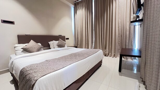 A modern hotel room with a large bed, a bedside table, and a window with curtains.