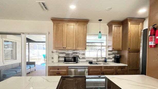 A modern kitchen with wooden cabinets, a built-in microwave, a sink, and a stove.