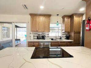 A modern kitchen with wooden cabinets, a built-in microwave, a sink, and a stove. - This is THE ONE! 3Br 2Ba+Pool, 10 Min to anywhere! (Port Orange)