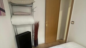 A bedroom with a bed, a wardrobe, and a small table with a vase. - Your Perfect Escape Seasonal (Madrid)