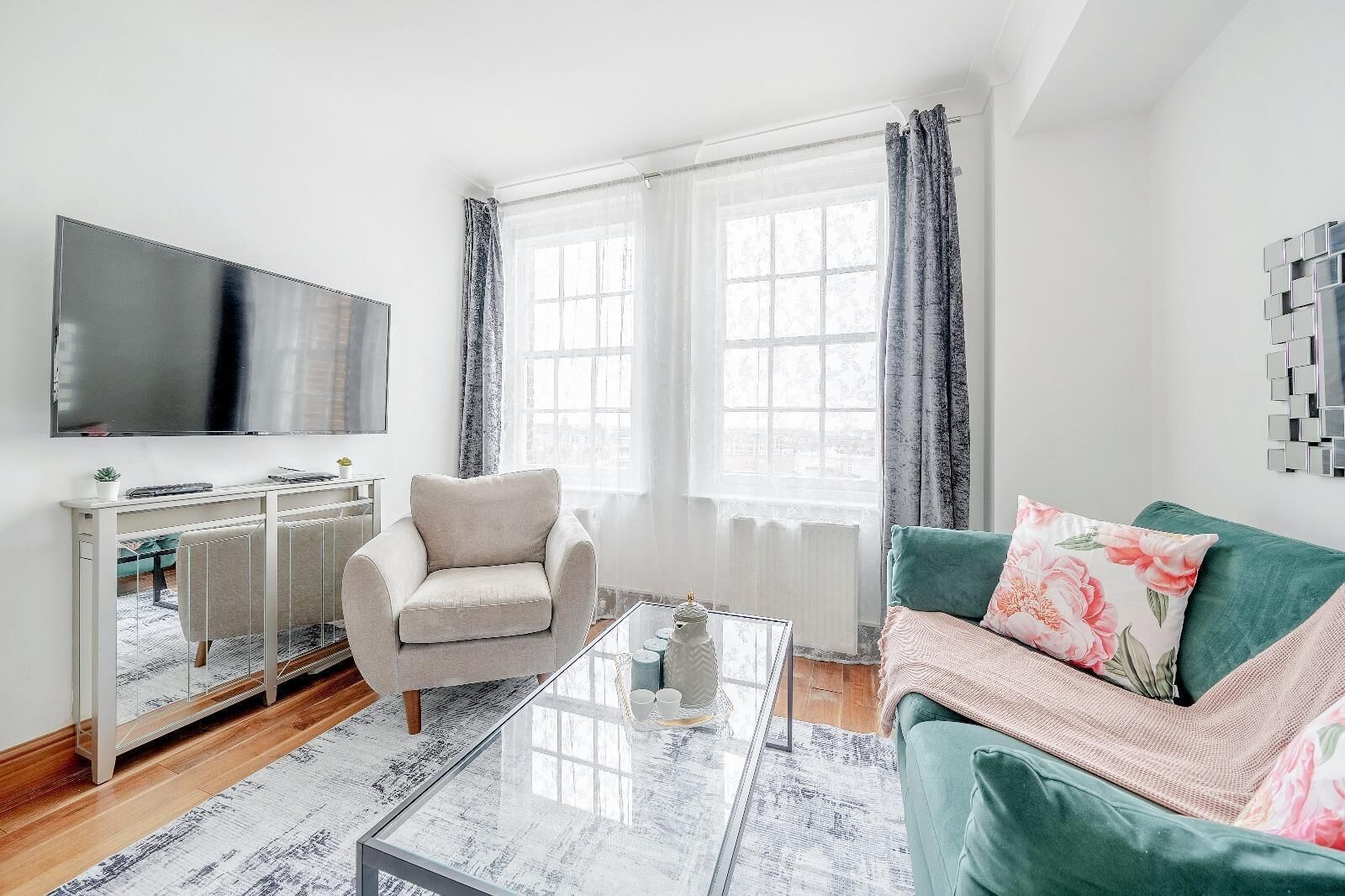 A living room with a TV, a sofa, a chair, a coffee table, and a window with curtains.
