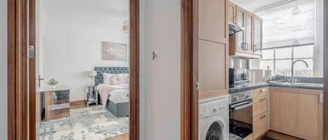 Un appartement compact comprenant une chambre, une kitchenette et un espace buanderie.