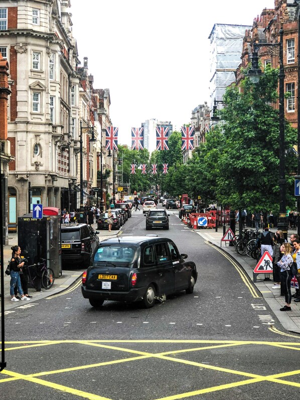 A street with buildings, flags, and cars. - Forset Court Residences (London)