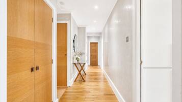 A hallway with wooden flooring, white walls, and doors.