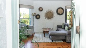 Un salon avec un canapé gris, un mur blanc et des œuvres d’art décoratives.