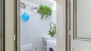 Ein kleines Badezimmer mit Waschmaschine, Toilette und einem kleinen Waschbecken.