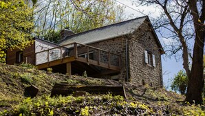 Ein Steinhaus mit einer Holzterrasse und einer Steintreppe, die zum Eingang führt.