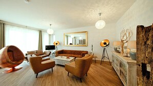 A modern living room with a sofa, armchairs, a coffee table, and a unique spherical chair.