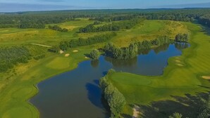 An aerial view of a golf course with multiple water bodies and sand bunkers.