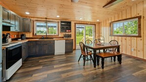 Una cocina moderna con armarios de madera, lavavajillas y una zona de comedor con mesa y sillas de madera.