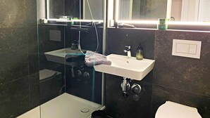 Ein modernes Badezimmer mit einer Duschkabine aus Glas, einem weißen Waschbecken und einem Spiegel darüber.
