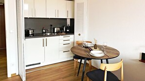 Eine kleine Küche mit weißen Schränken, einem runden Esstisch und Holzboden.