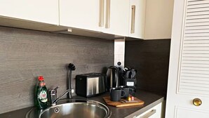 Eine Küche mit einer Edelstahl-Spüle, einem Toaster, einer Kaffeemaschine und einer Flasche Geschirrspülmittel.