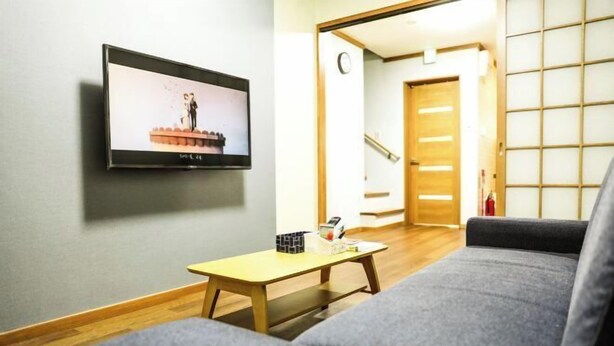 Una sala de estar con un sofá, una mesa de centro y un televisor montado en la pared.