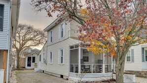 A two-story house with a covered porch and a brick driveway.