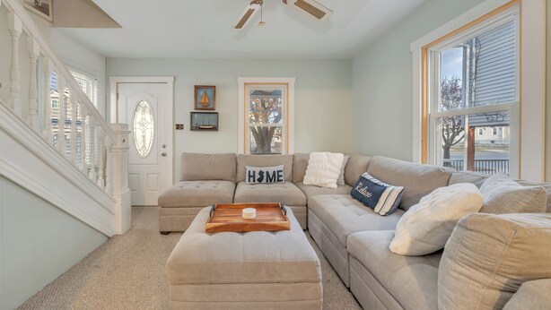 A spacious living room with a beige sofa set, a wooden coffee table, and a ceiling fan.