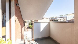 A small, enclosed balcony with a white awning, a tiled floor, and a view of neighboring buildings.