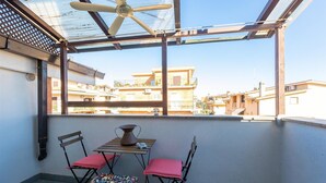 A balcony with a table and chairs, a ceiling fan, and a view of neighboring buildings.