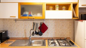 A kitchen with a stainless steel sink, a gas stove, and wooden cabinets.