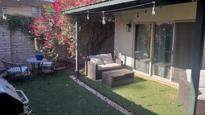A covered patio area with a seating arrangement, artificial grass, and a cactus plant. - Walk to Spring Training  - 3BR home in Scottsdale (Scottsdale)