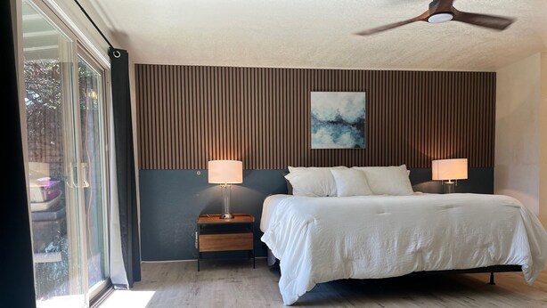 A bedroom with a bed, two bedside tables with lamps, a ceiling fan, and a window with a view of trees. - Walk to Spring Training  - 3BR home in Scottsdale (Scottsdale)