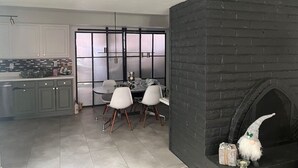 A modern kitchen with grey cabinets, a round dining table with four chairs, a black brick fireplace, and a frosted glass door. - Walk to Spring Training  - 3BR home in Scottsdale (Scottsdale)