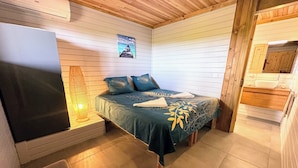 Un dormitorio con cama, mesita de noche, lámpara y vistas al baño.