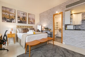 Enjoy a comfortable stay in this stylish room with a bed, bedside table, and seating area, featuring a large window with city views and a unique brick wall.