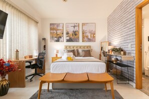 Relax in a stylish room with a large bed, desk, and seating area, featuring a flat-screen TV and comfortable chair.