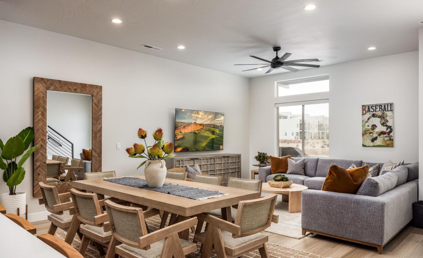 Un salon moderne comprenant un coin repas, un canapé gris et un ventilateur de plafond.
