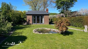 Una casa moderna con fachada de ladrillo, amplios ventanales y un pequeño jardín con un estanque.