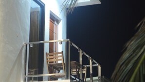 A balcony with a chair and a table, a door, and a window. - Ocean View (Naval)