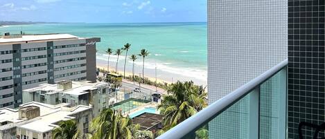 A balcony with a view of the beach and ocean.