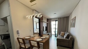 A modern living room with a dining area, a sofa, and a TV. - Edificio Liv P. Verde Apt 706 (Maceió)
