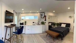 A modern, compact living space with a kitchenette, a dining area, and a bedroom.