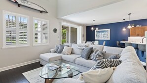 Una sala de estar moderna con un sofá modular, una mesa de centro de vidrio y una tabla de surf en la pared.