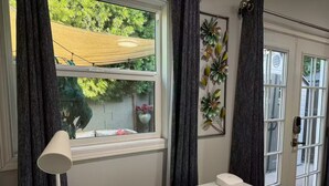 A room with a white table, a lamp, and a window with curtains.