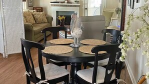 Un comedor con una mesa redonda, sillas negras y una lámpara de araña.