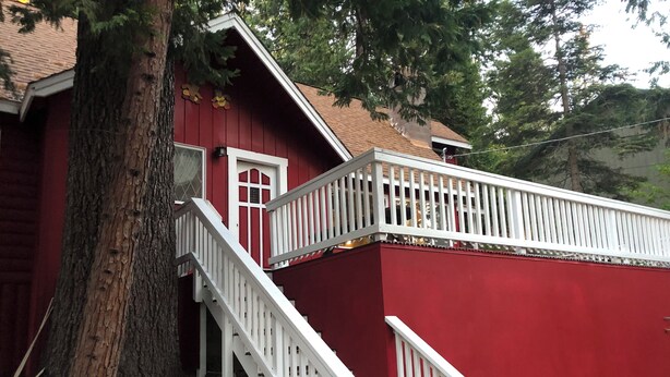 A red building with a white staircase leading to a balcony. - Charming Ski cabin with WiFi near Dodge Ridge, great for family or small group. (Mi-Wuk Village)