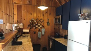 A kitchen with wooden walls, a refrigerator, a stove, and various kitchen utensils. - Charming Ski cabin with WiFi near Dodge Ridge, great for family or small group. (Mi-Wuk Village)