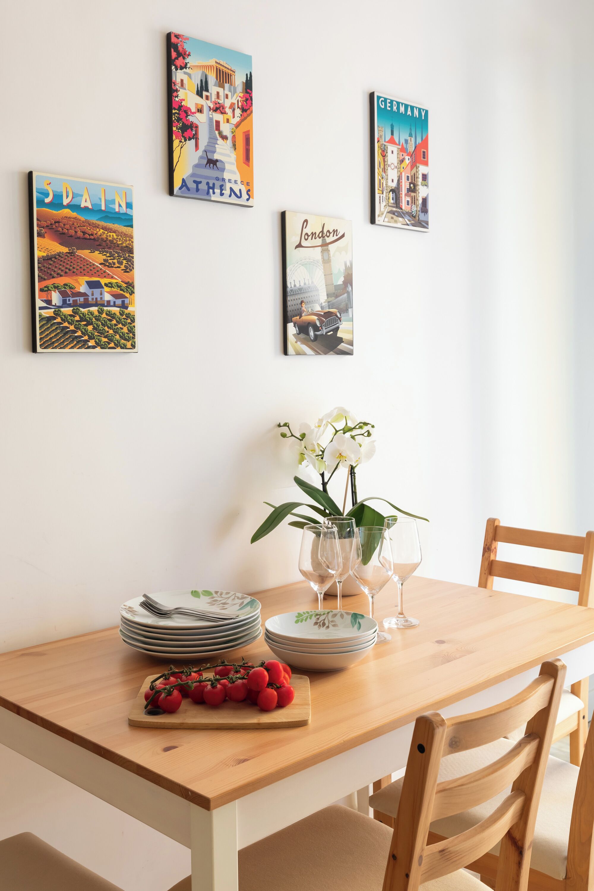 A dining table with plates, glasses, and a vase of flowers.
