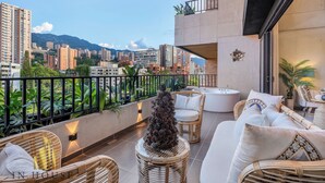 A balcony with wicker furniture, a Christmas tree, and a city view. - Elegant/Modern Apt in Poblado - Morph 1201 (Medellín)