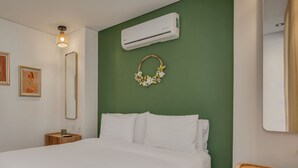 A hotel room with a bed, a wall-mounted air conditioner, a mirror, and two framed artworks. - Elegant/Modern Apt in Poblado - Morph 1201 (Medellín)