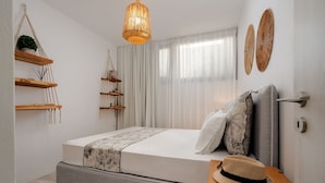 Un dormitorio moderno con una cama, repisas de madera, una lámpara colgante y un adorno en la pared.