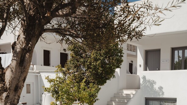 Un área de piscina moderna con sillones blancos y una escalera que lleva a un edificio.