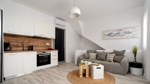 Una cocina moderna con armarios blancos, encimera de madera y horno empotrado.