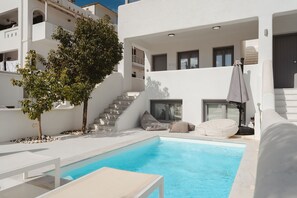 Ein moderner Poolbereich mit einem klaren, blauen Pool, weißen Liegestühlen und einer Treppe, die zu einer erhöhten Ebene führt.