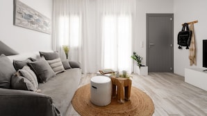 Un salón moderno con un sofá gris, una mesa de centro redonda de madera y una puerta gris.