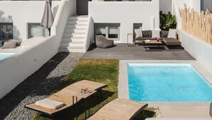 En moderne, hvid bygning med swimmingpool, udendørs siddepladser og en trappe til en balkon.